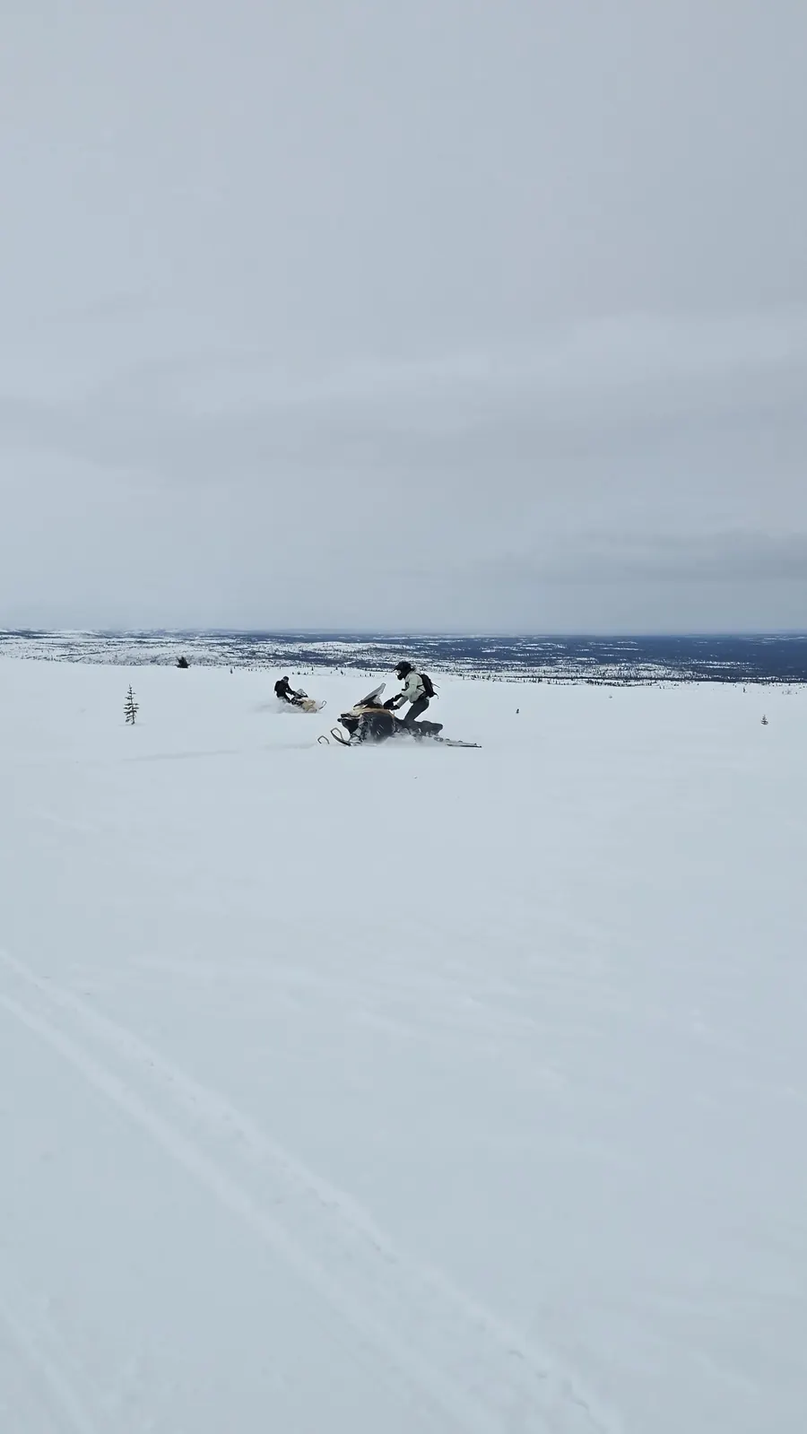 A single rider crossing a wide snowfield toward distant hills